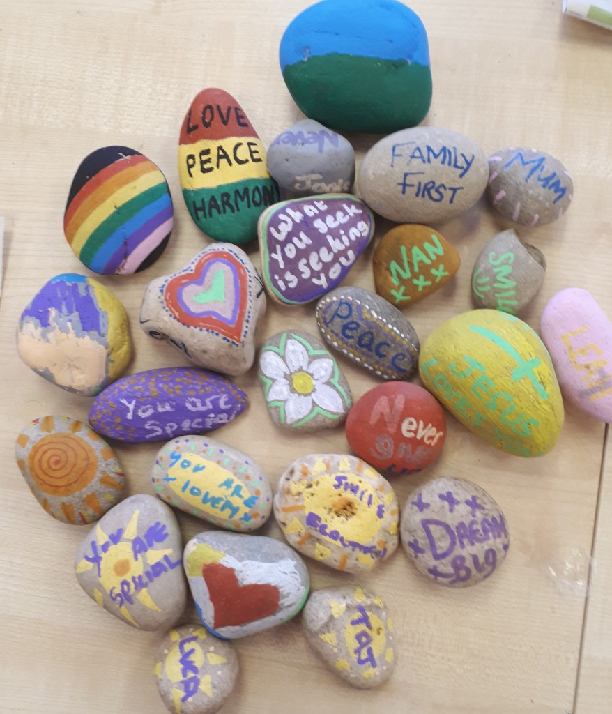 A collection of small stones painted in bright colours, some with messages of peace